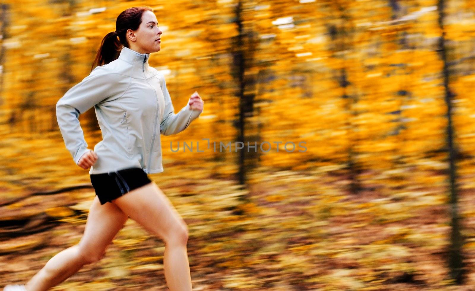 Beautiful young woman running in a fall forest.