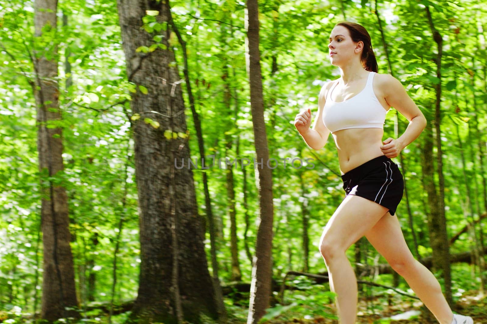 Beautiful young woman runner in a green forest.
