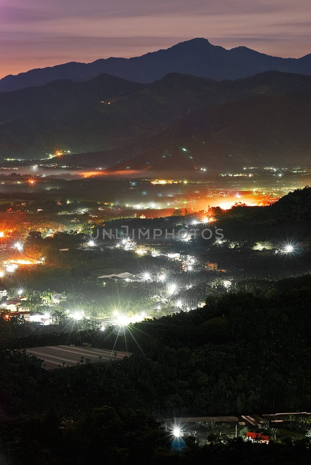 Rural night scene with mist over hill and buildings.