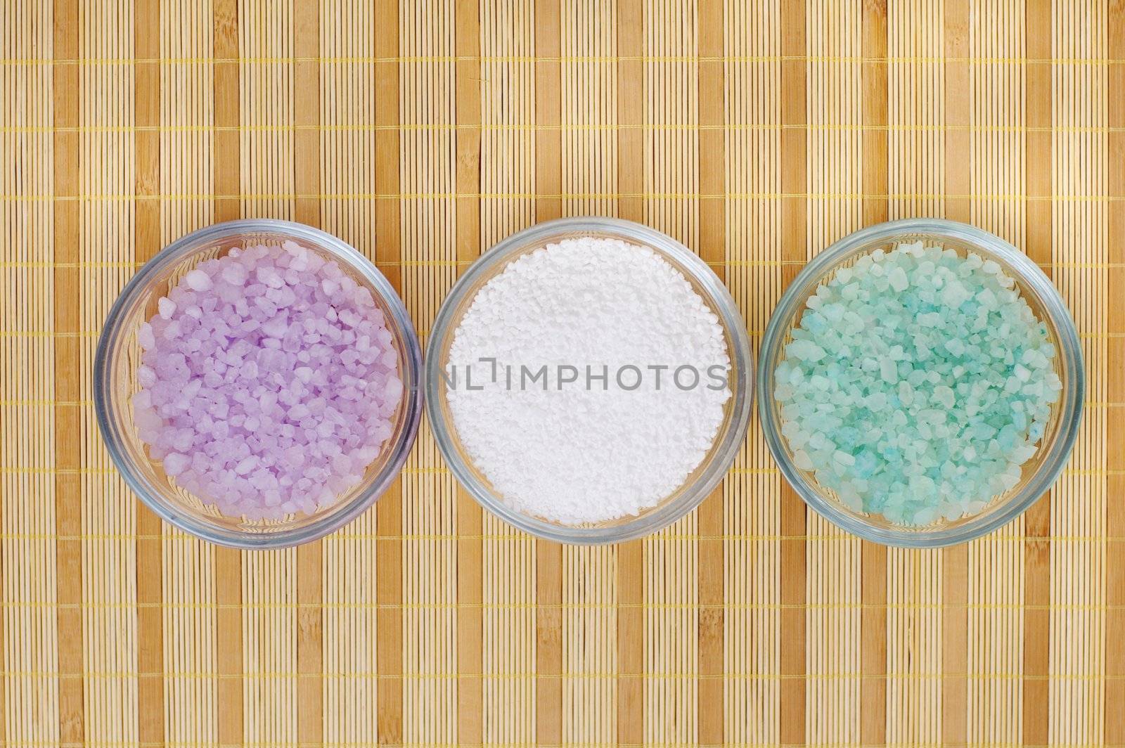 Colored bath salt displayed on top of a bamboo mat.