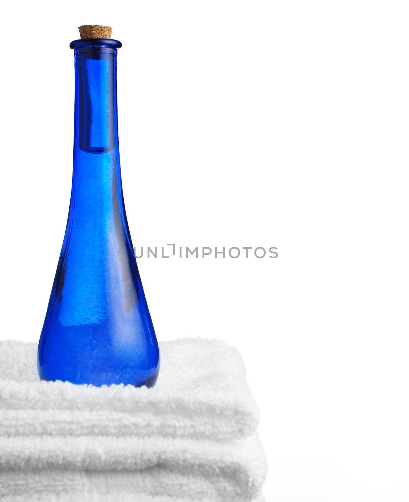 Blue glass corked bottle and towels against white.