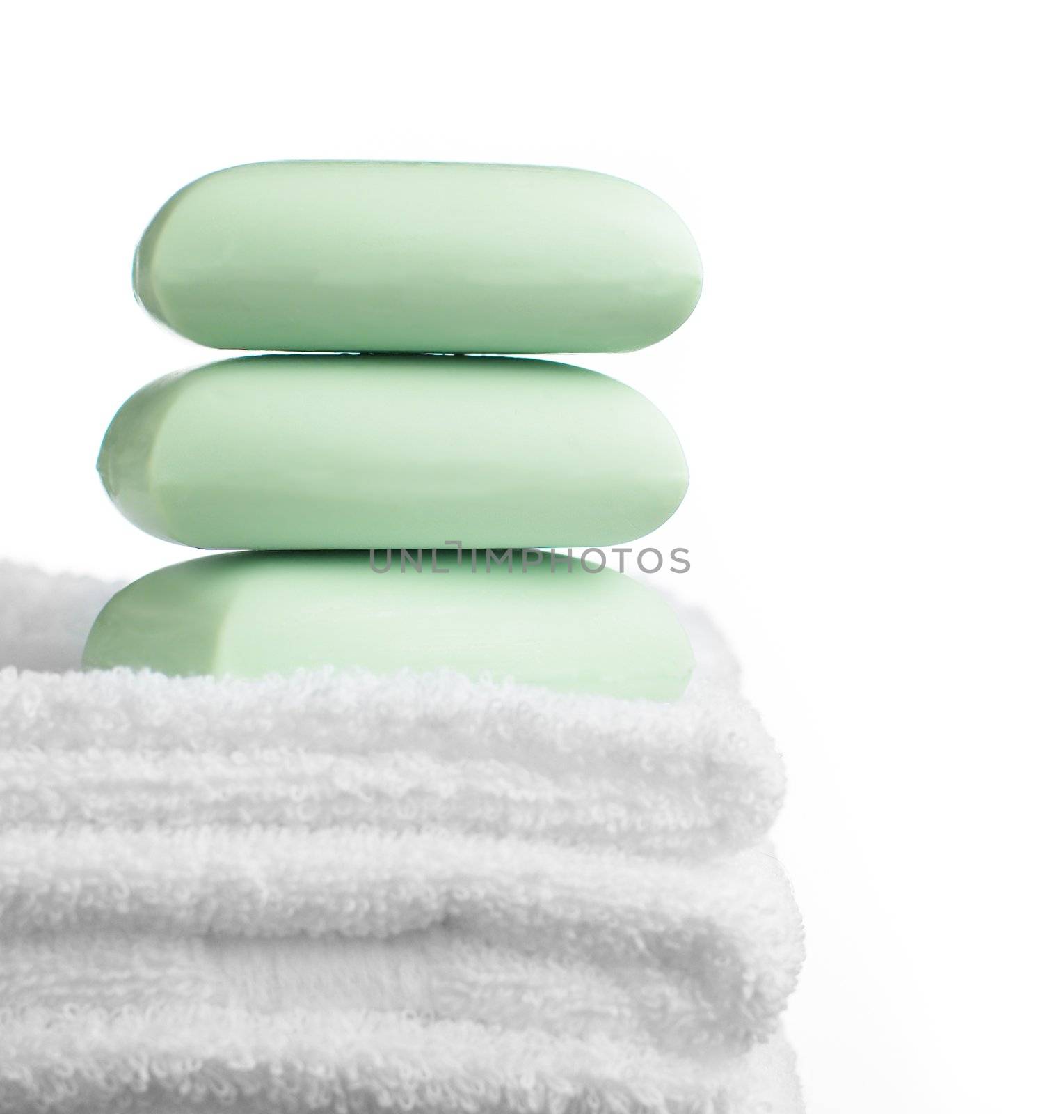 Stack of soap bars and towels against white.