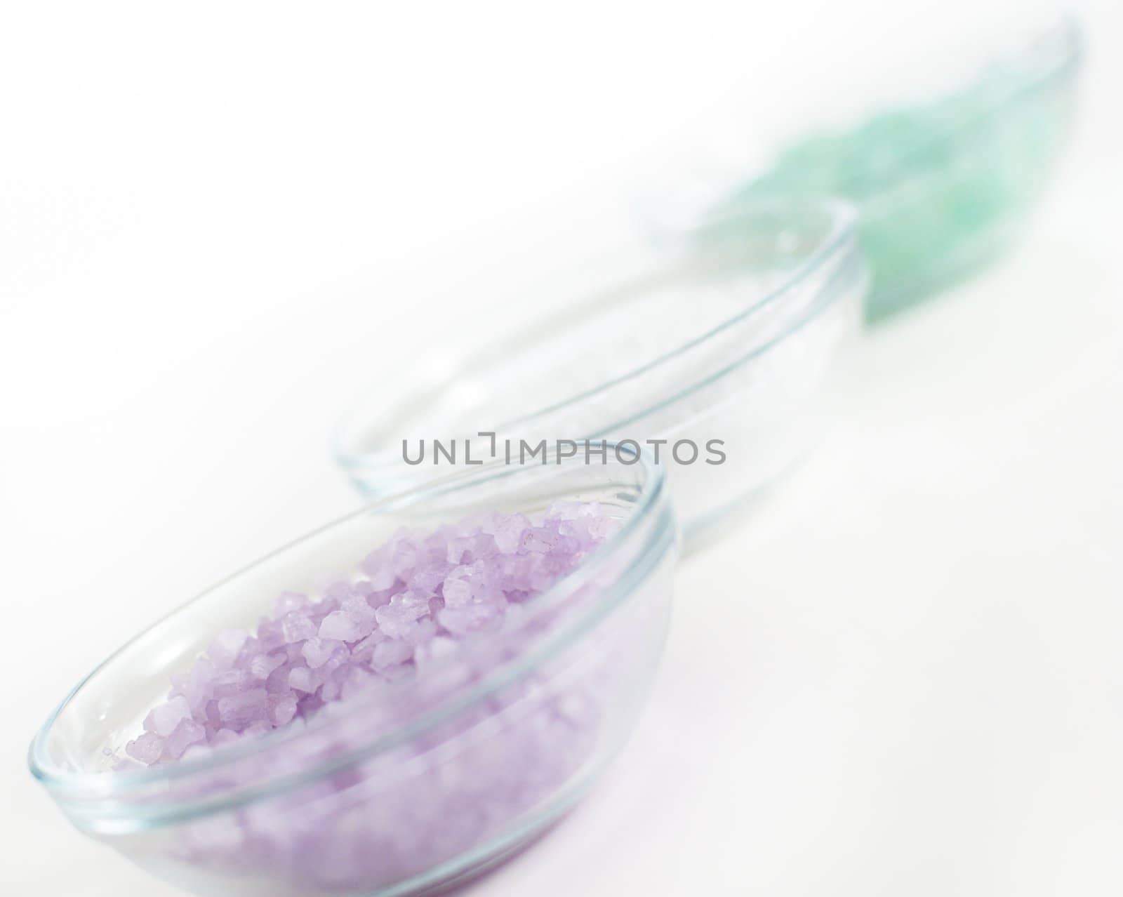 Bowls of colorful bath salt against a white background.