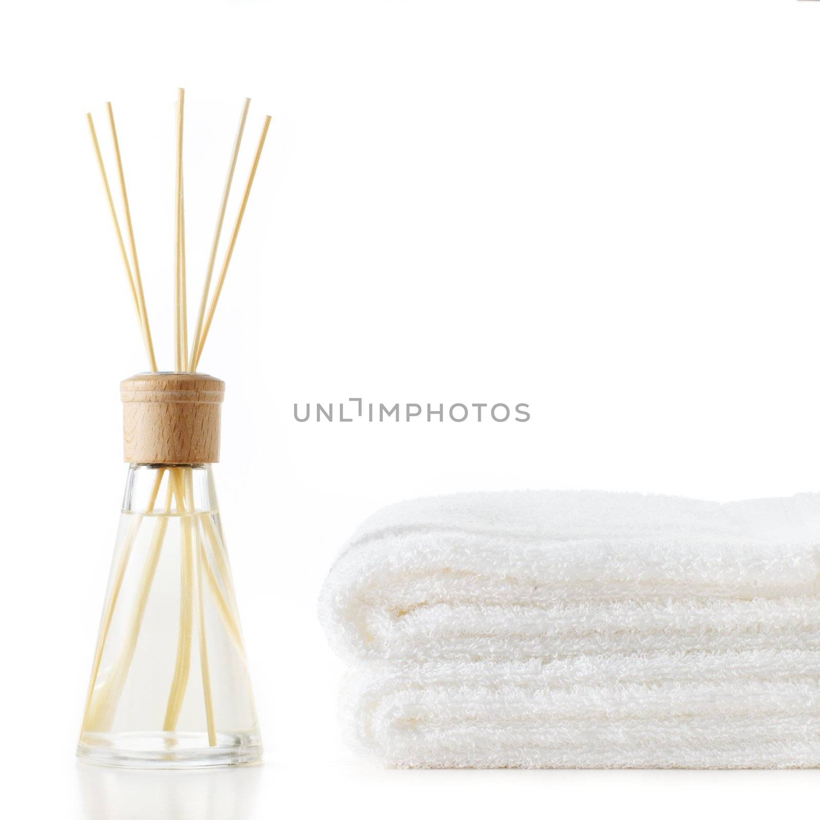 Diffuser and stack of towels against a white background.