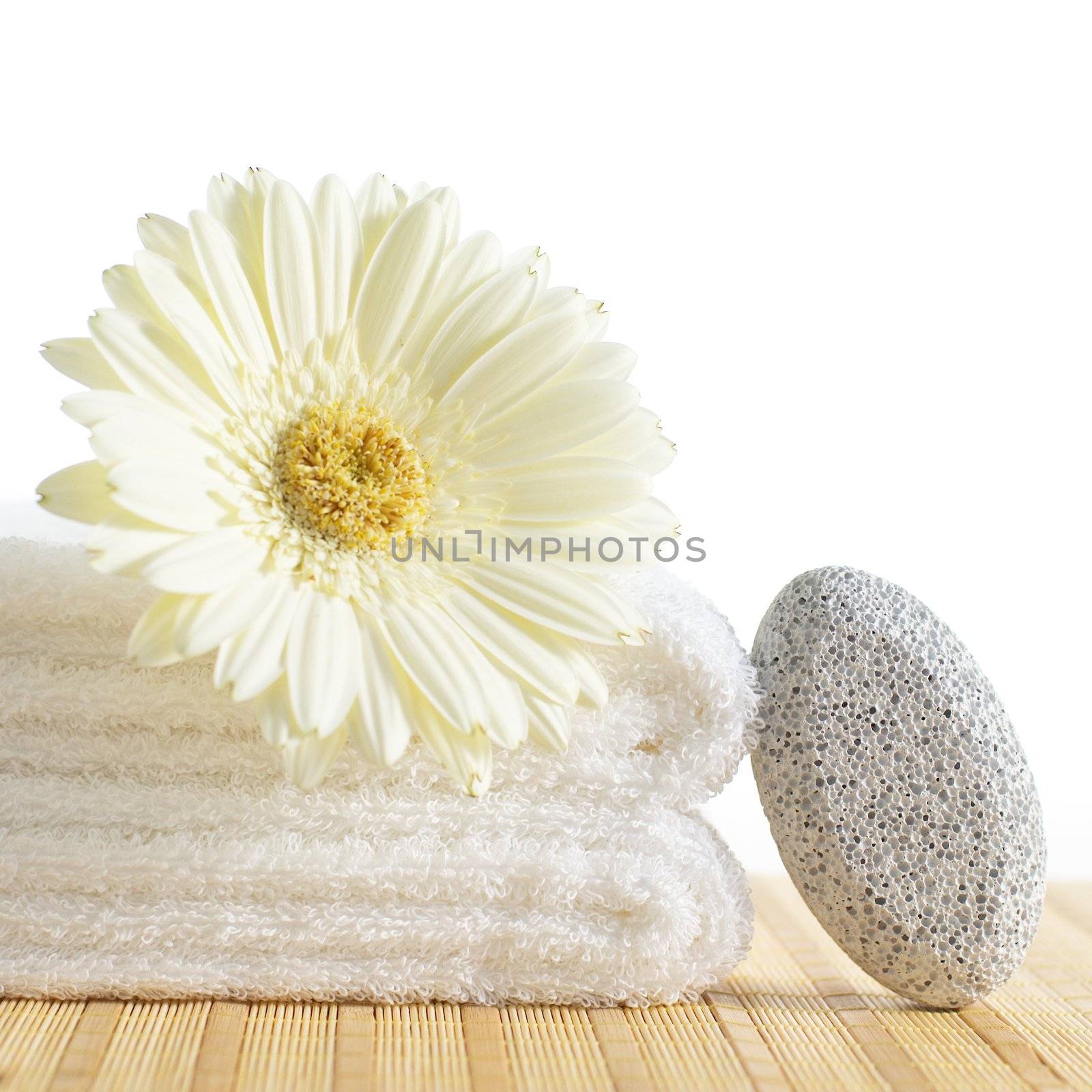Towels, pumice stone, and flower against a white background.