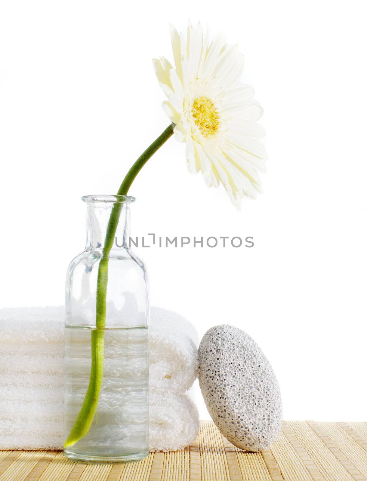 Flower, towels, and pumice stone against a white background.
