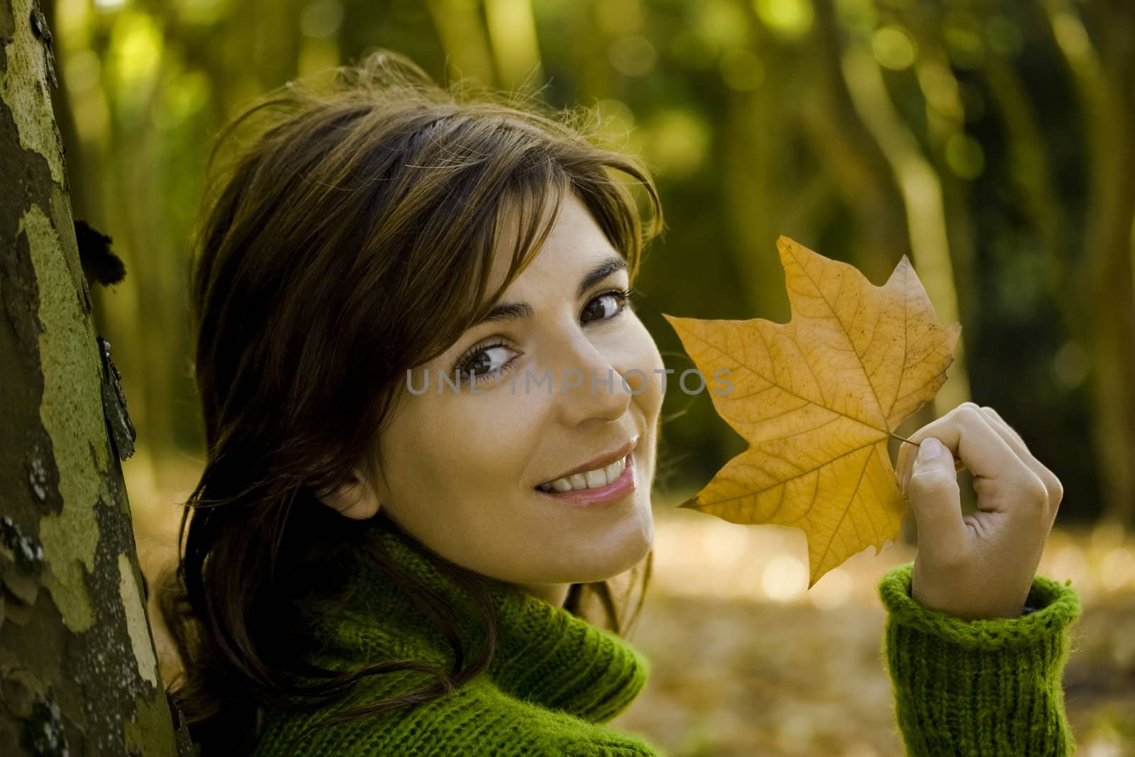 Close-up portrait of a beautiful young woman holding a leaf