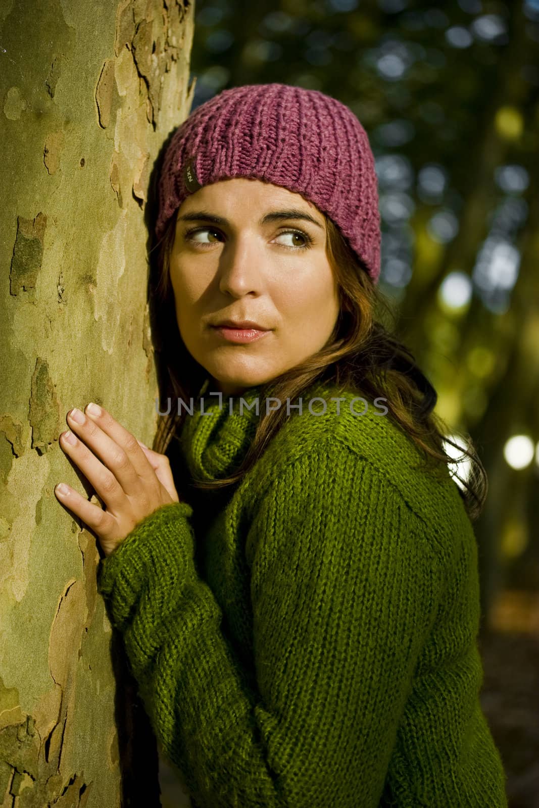 Autumn portrait of a beautiful young woman close to a tree