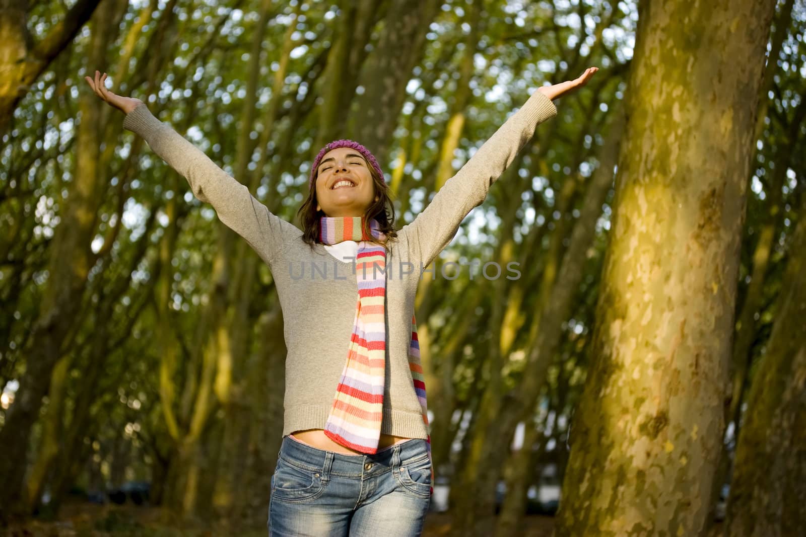 Beautiful happy young woman with open hands in the forest