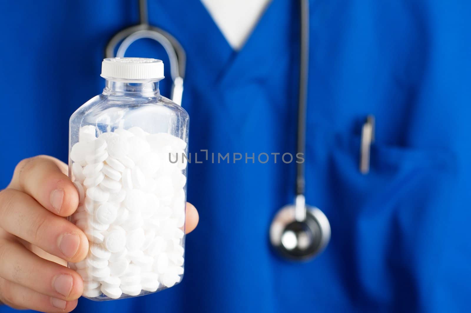 Pills being displayed in front of blue scrubs.