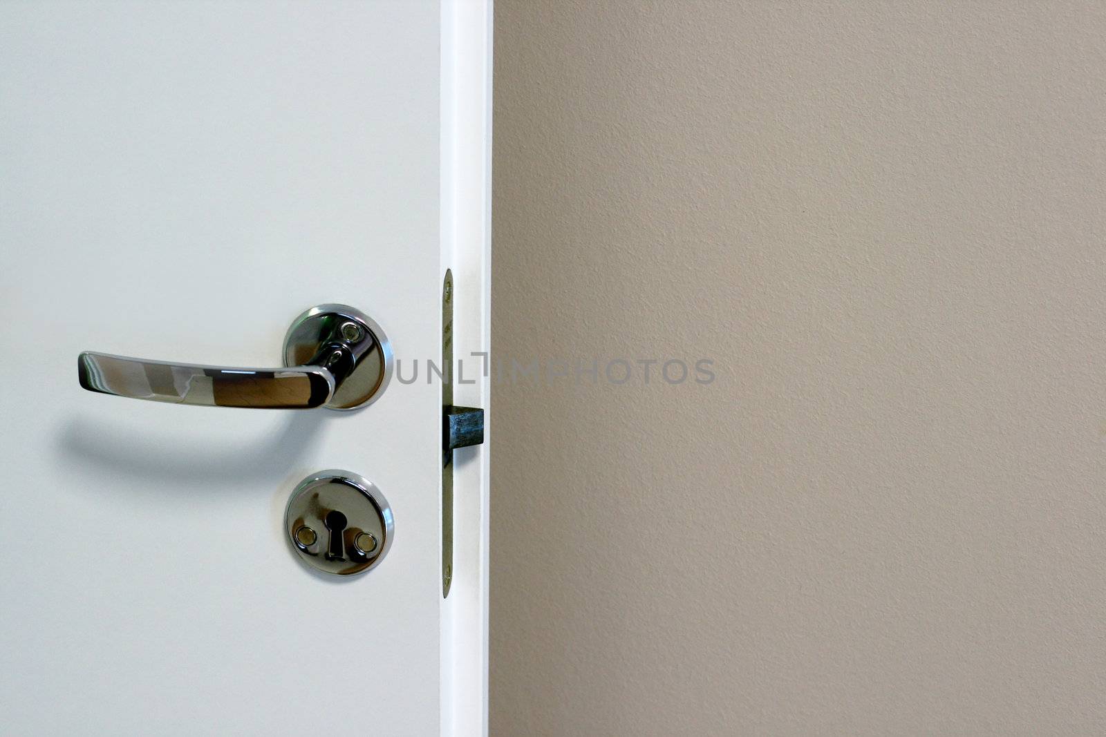 White door with the lock on a background of a wall