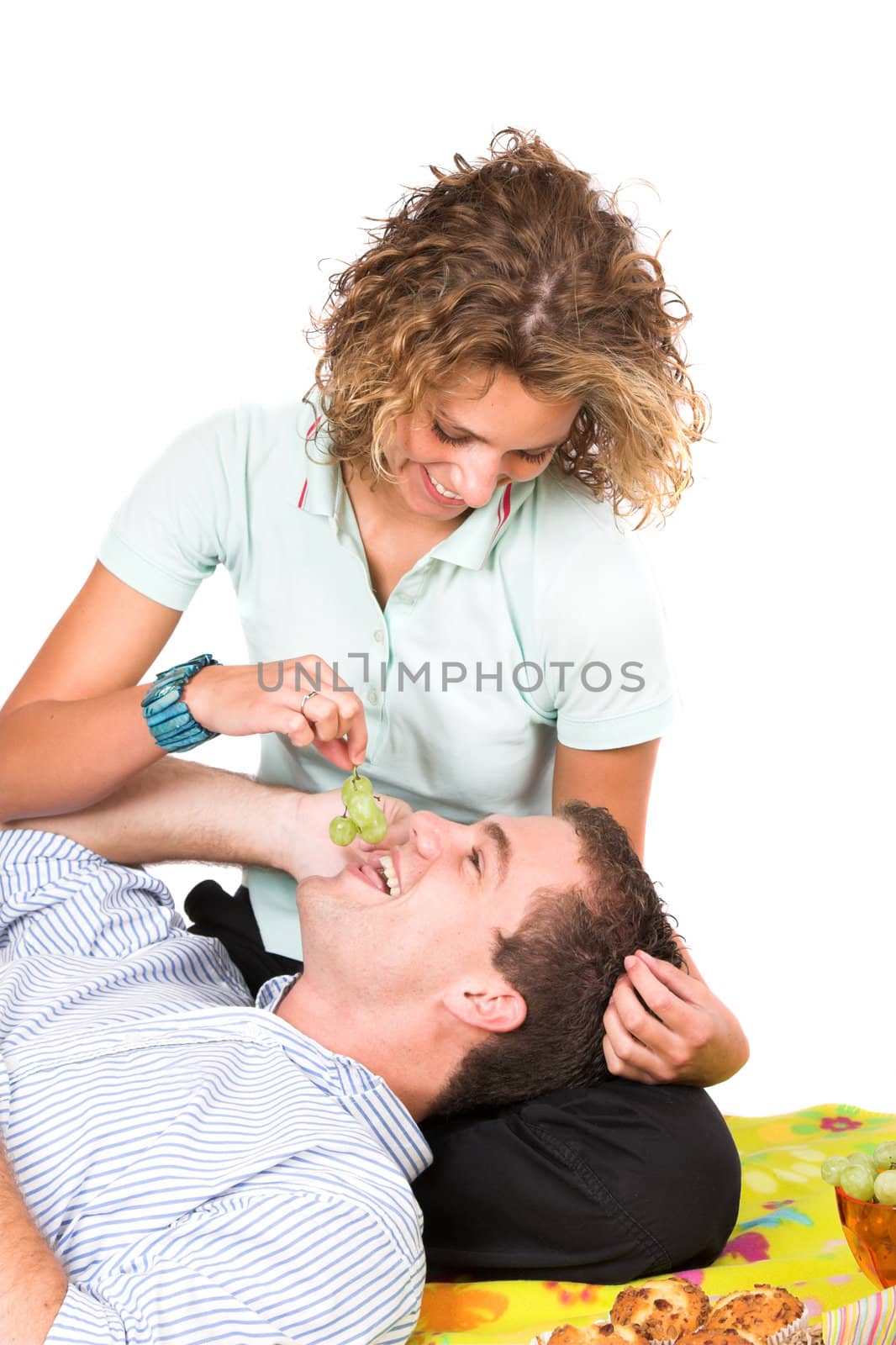 Girl trying to push grapes into her boyfriend's mouth while he is trying to have a phone conversation