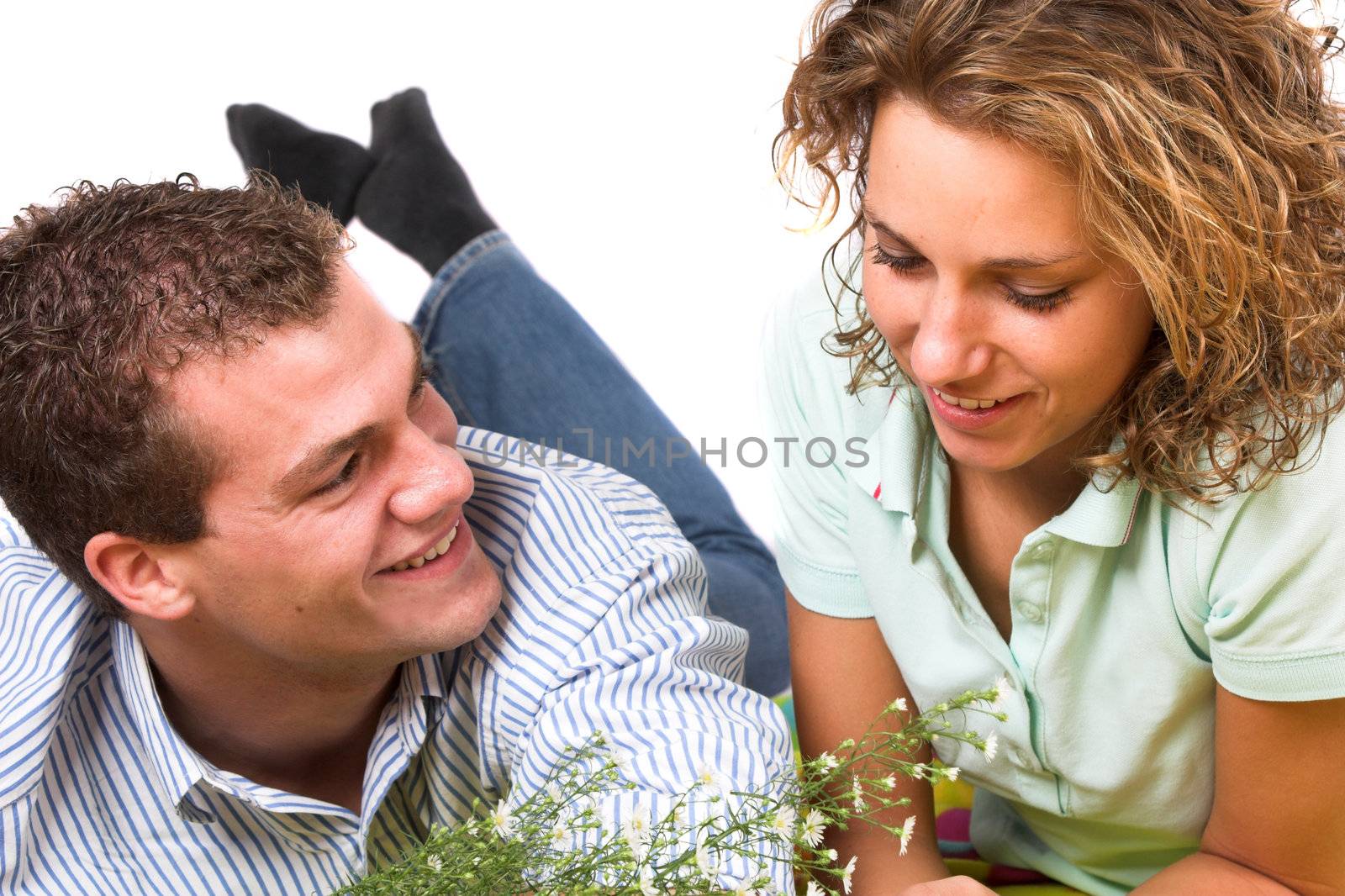 Boy and girl lying together on a picnic blanket, laughing and clearly in love
