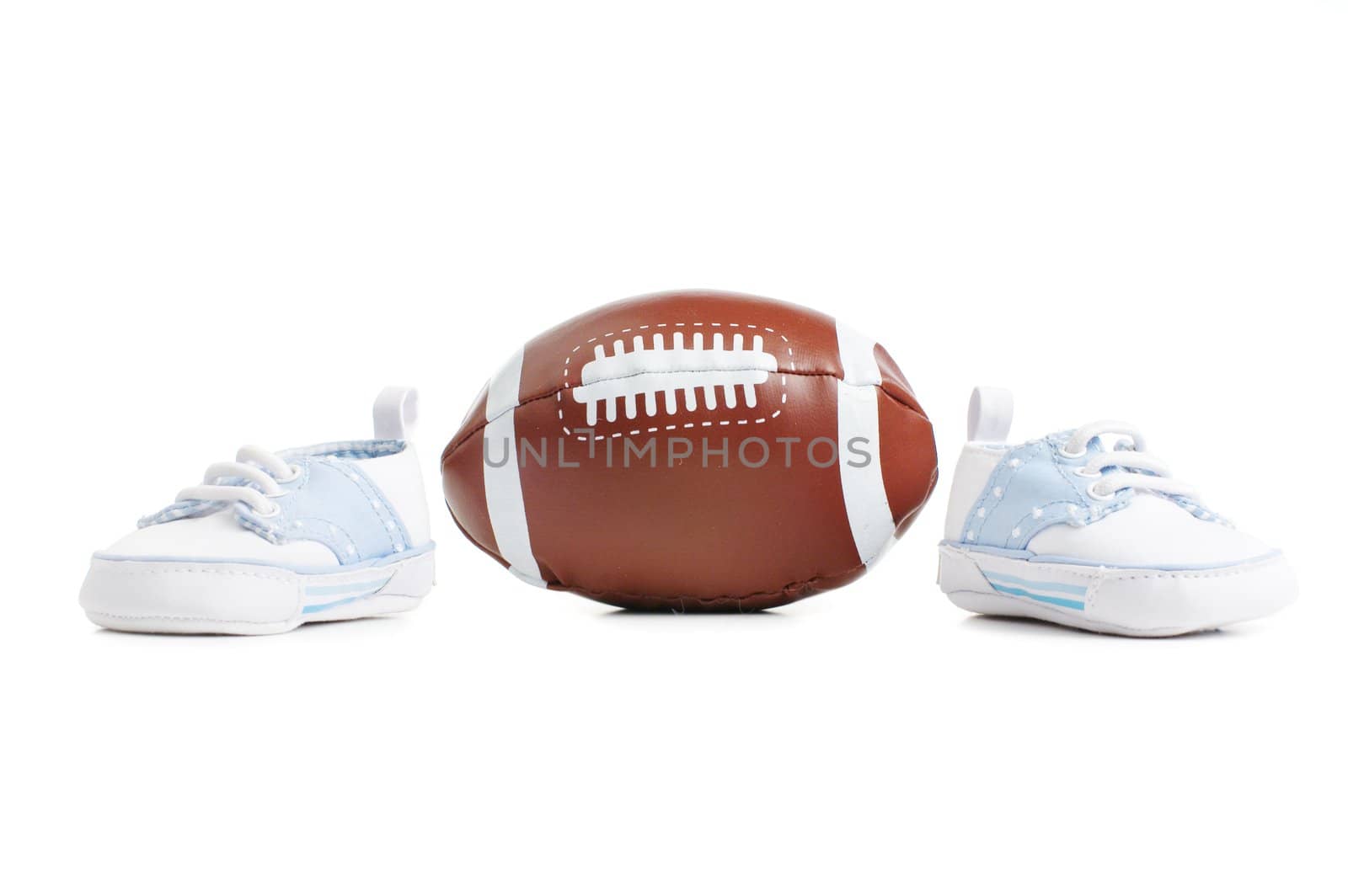 Football with baby shoes against a white background.