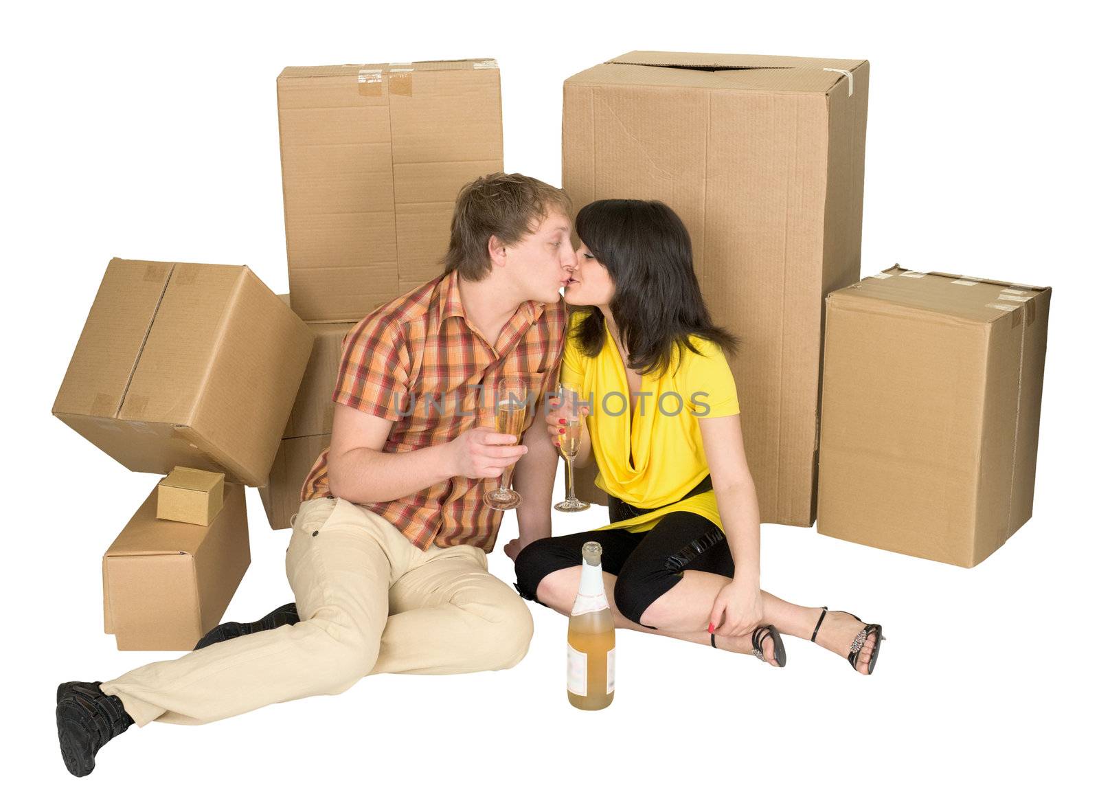 Girl and the guy drink champagne near boxes on a floor