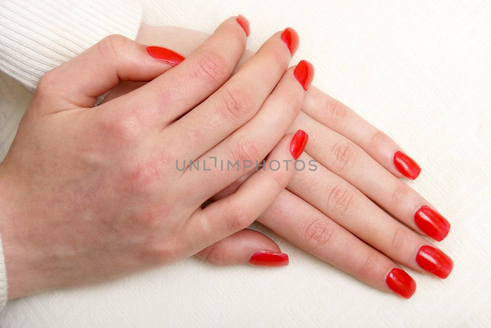 A girls freshly manicured hands pose on a pillow.