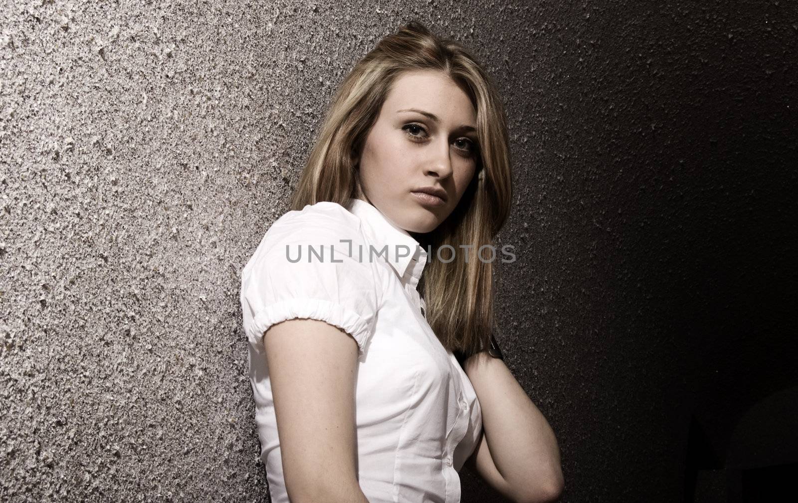 Portrait of a young pretty blonde on the wall background