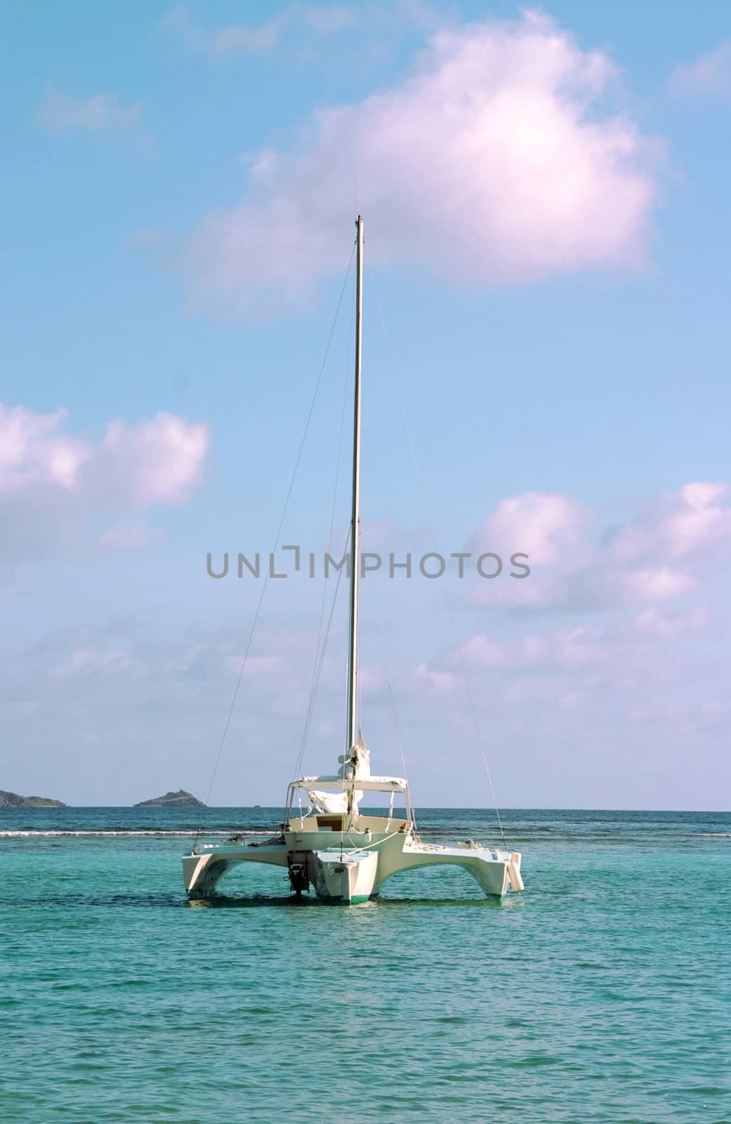 A Trimaran sailboat anchored in the bay of a paradise island setting.