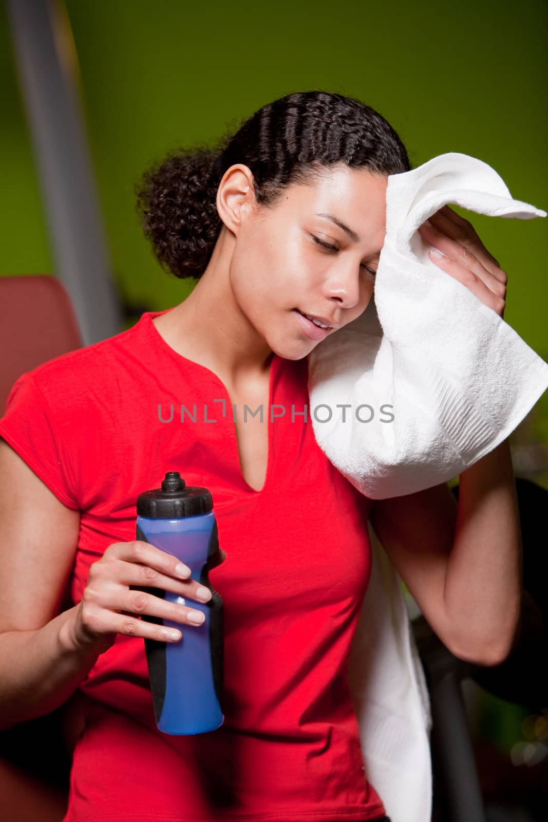 Attractive young girl in the gym wiping away the sweat