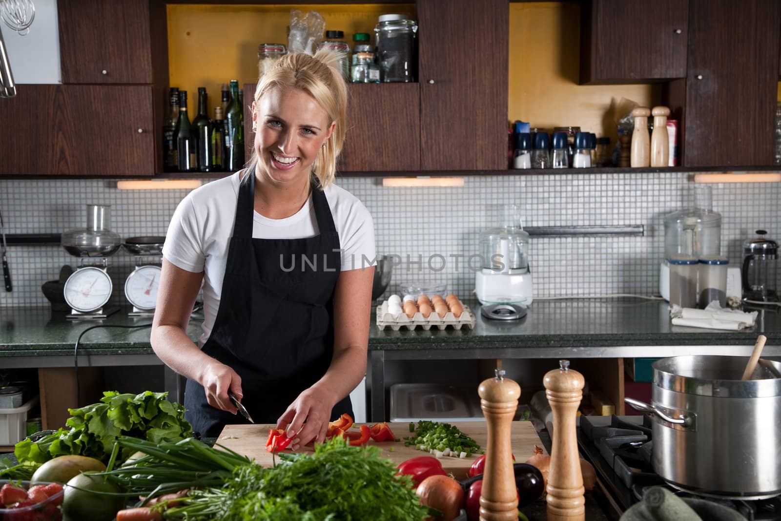 Pretty young blond female chef working in the kitchen