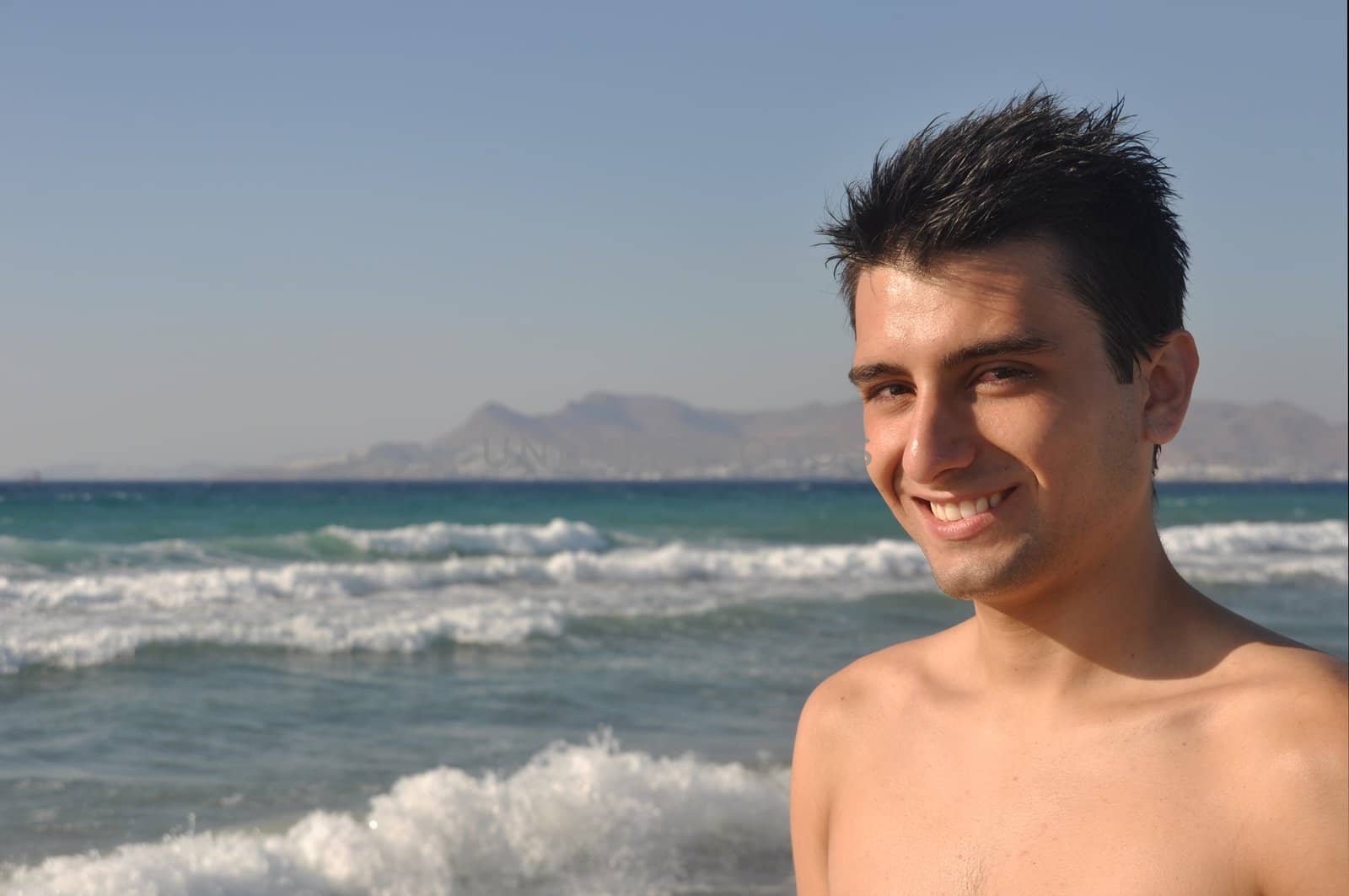 smiling young man at Kos beach in Greece (blue sky)