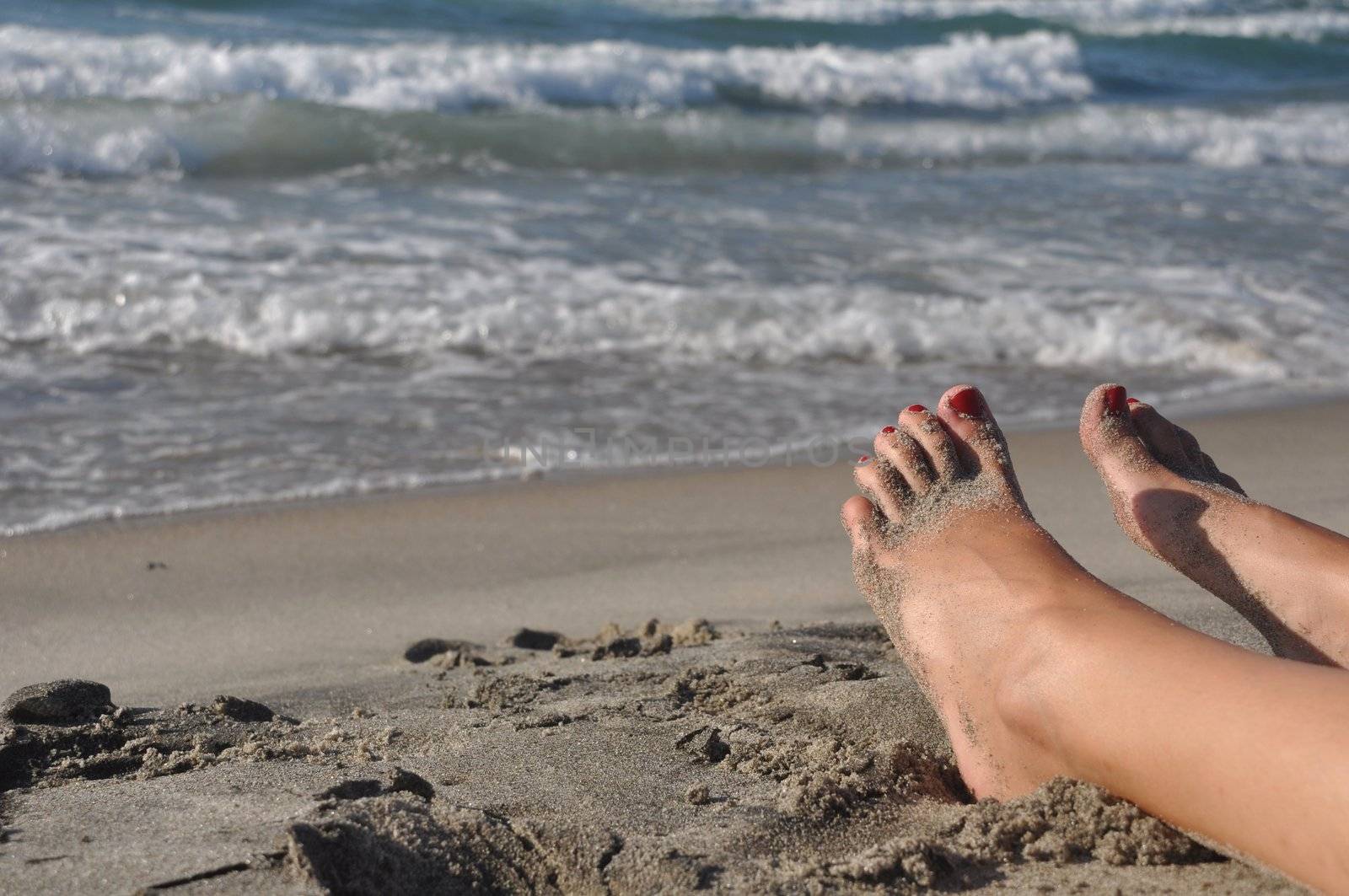 woman feet lying and relaxing on the beach
