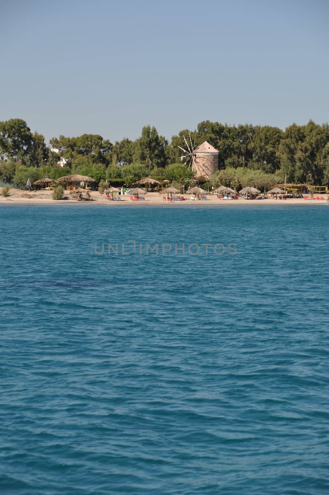 ancient windmill at Kos coastline and beach, Greece