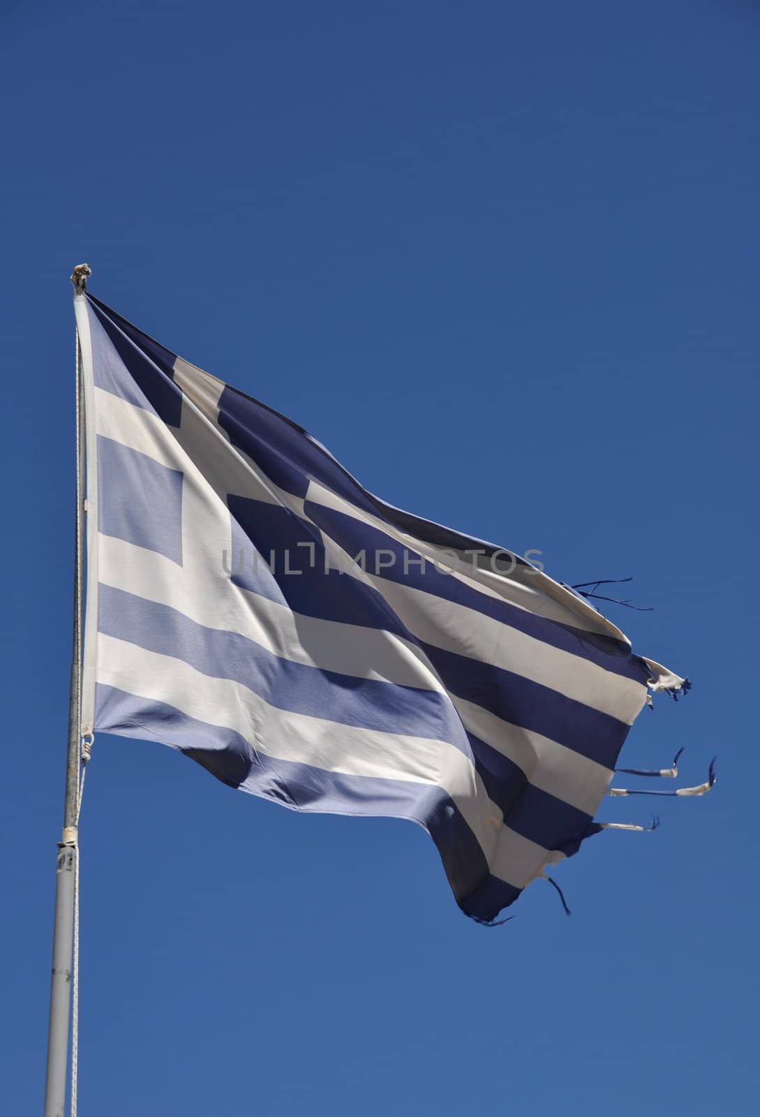 ripped flag of Greece against blue sky background