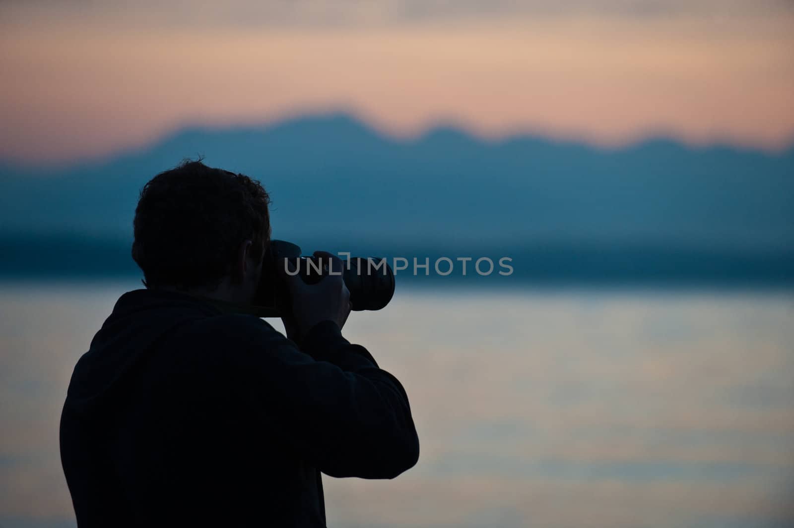 man with camera, mountains behind, at sunset