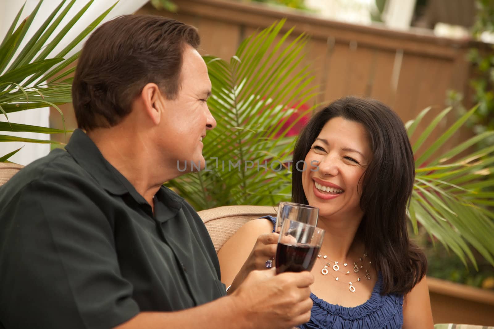 Attractive Hispanic and Caucasian Couple Drinking Wine by Feverpitched