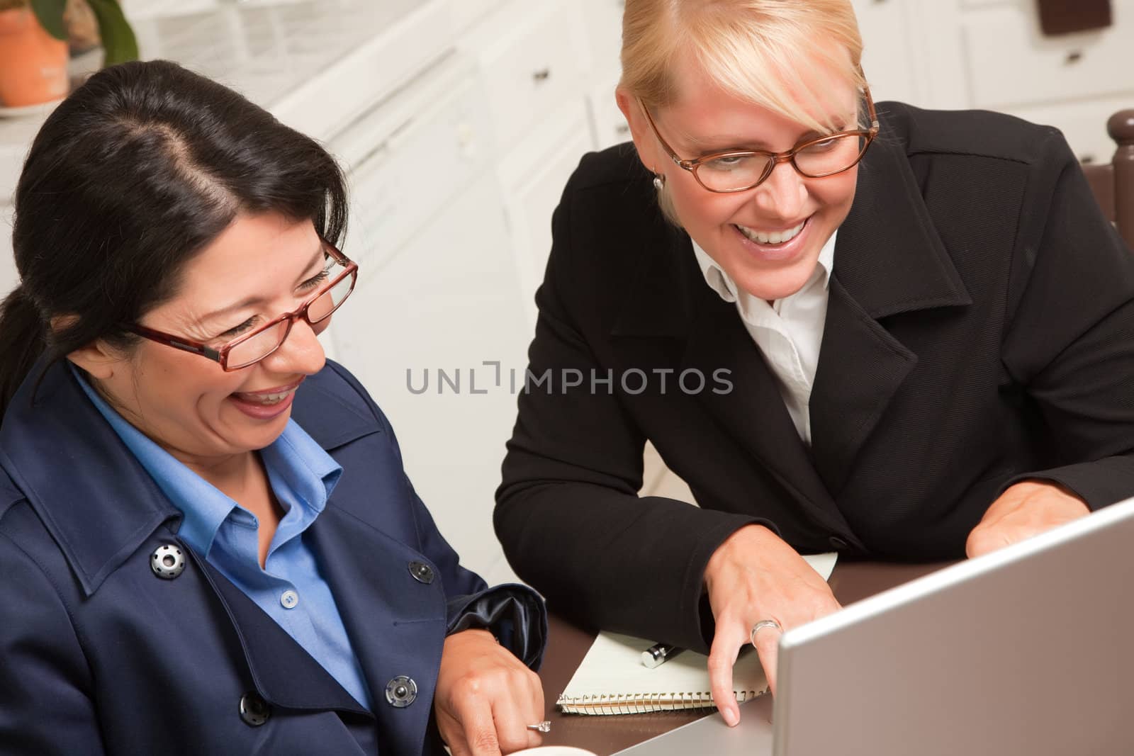 Businesswomen Working on the Laptop Together in the Kitchen.