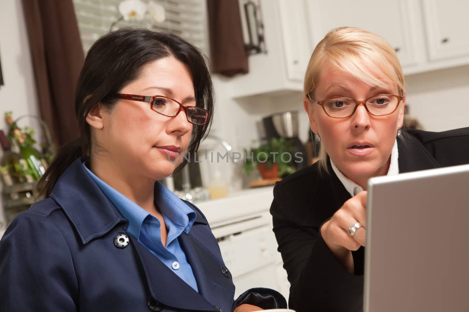 Businesswomen Working on the Laptop Together in the Kitchen.