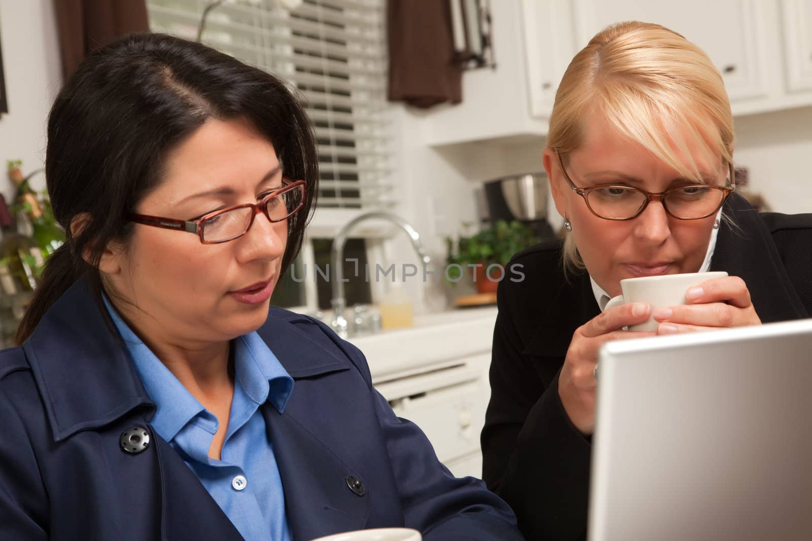 Businesswomen Working on the Laptop Together in the Kitchen.