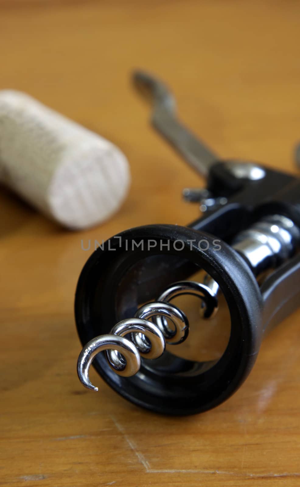 A corkscrew and a cork sitting on a wooden table.