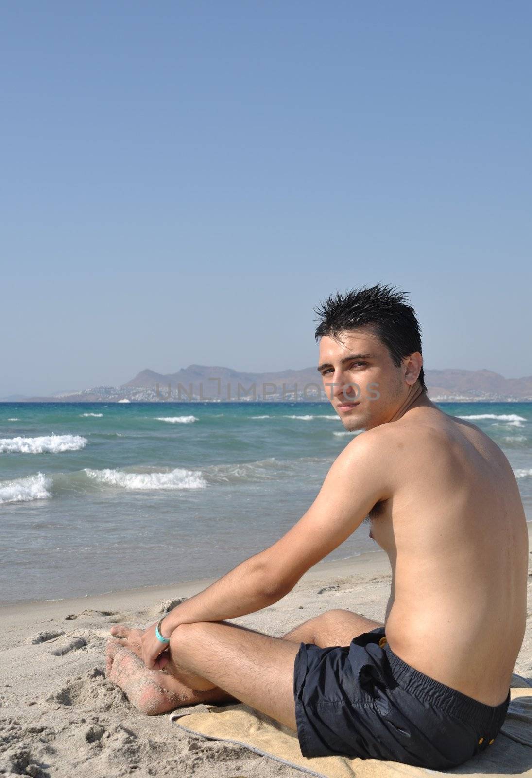 young man relaxing at Kos beach in Greece (blue sky)