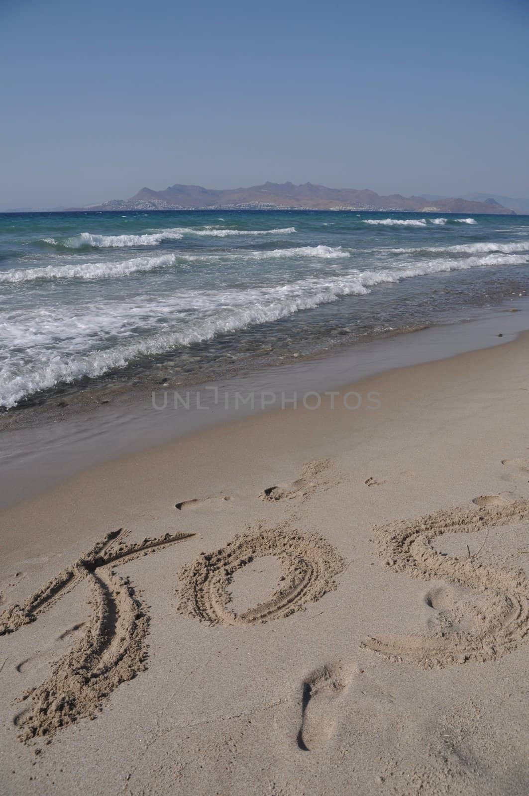 Kos written on a sandy beach in Kos, Greece (Turkey on the background)