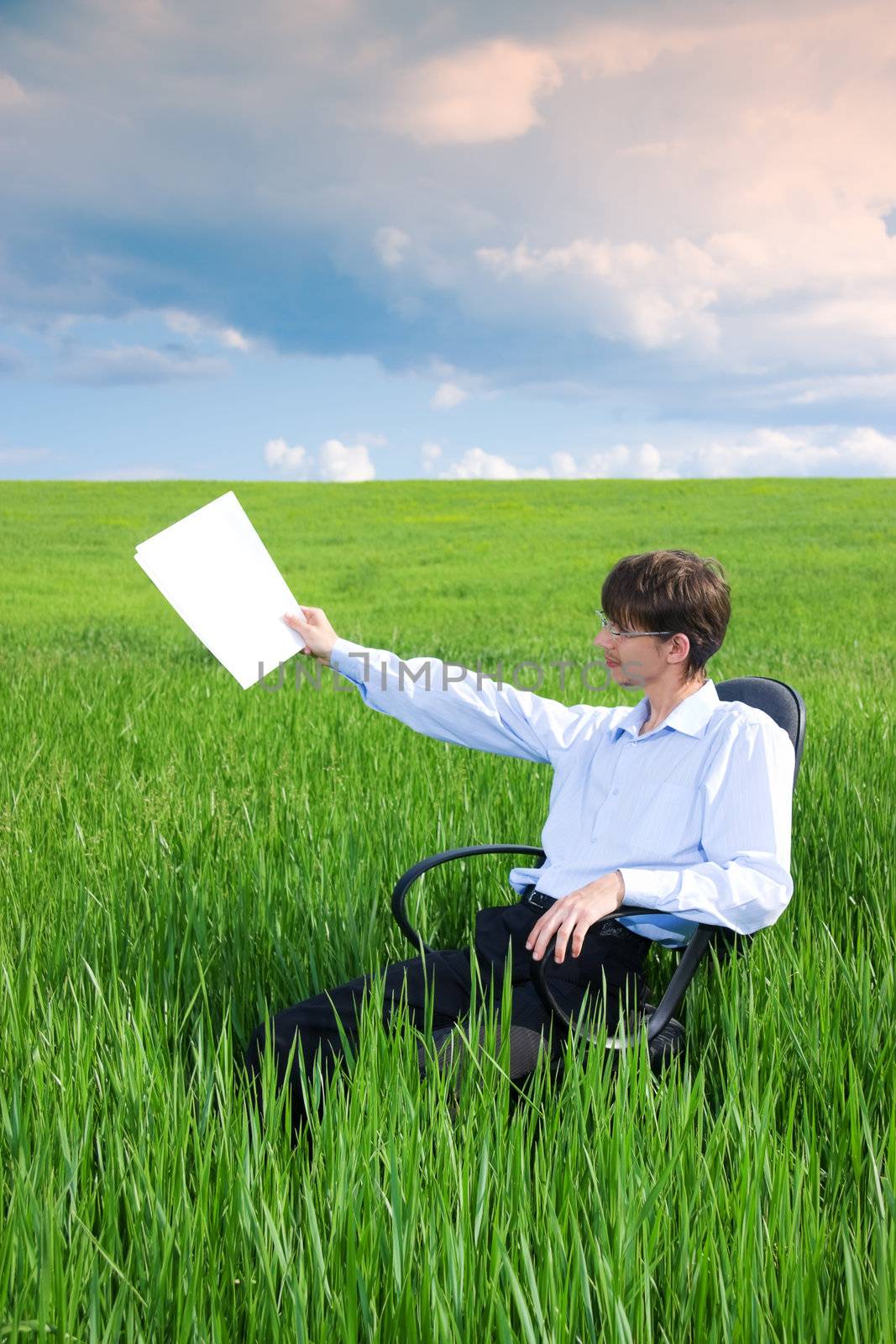 Businessman working on green grassland under blue sky