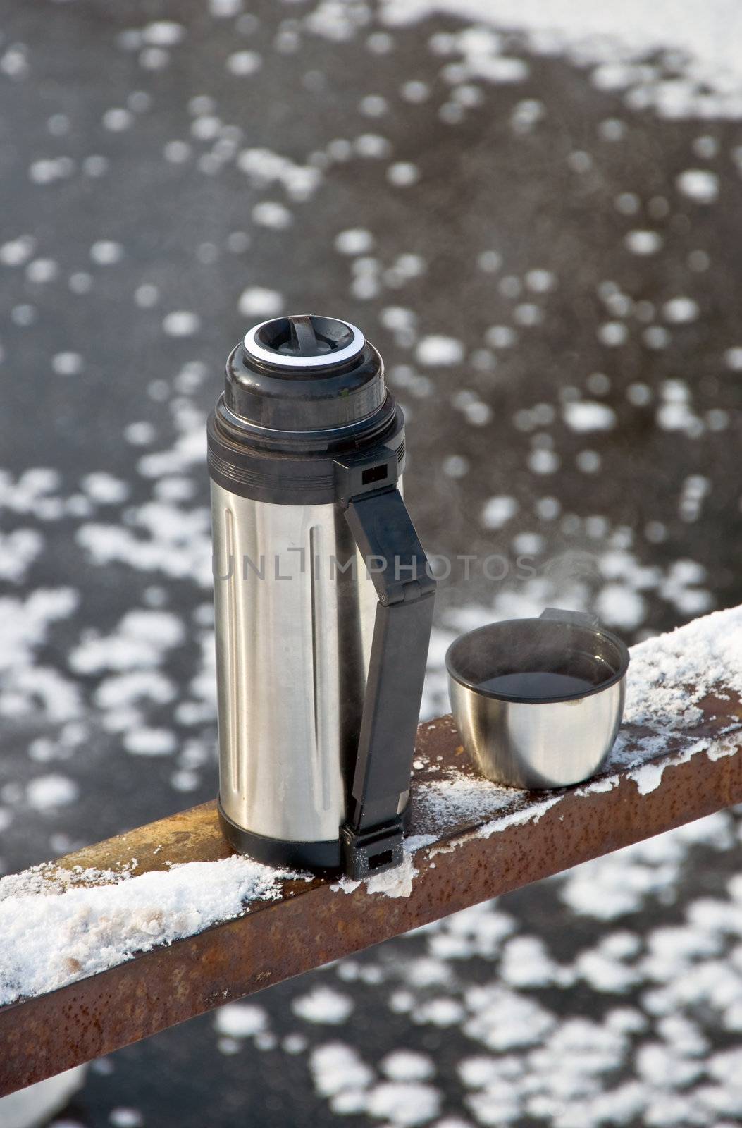 Metal thermos with hot tea drink. Winter.