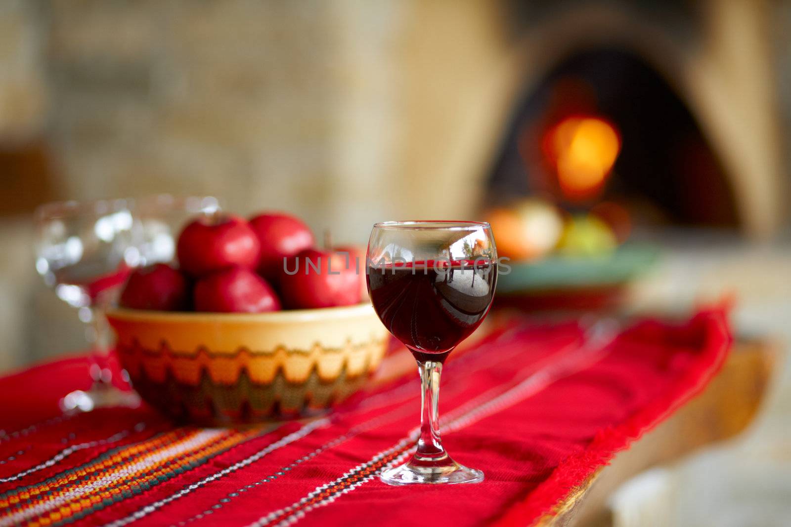 Glass of red wine on a table, behind a fireplace