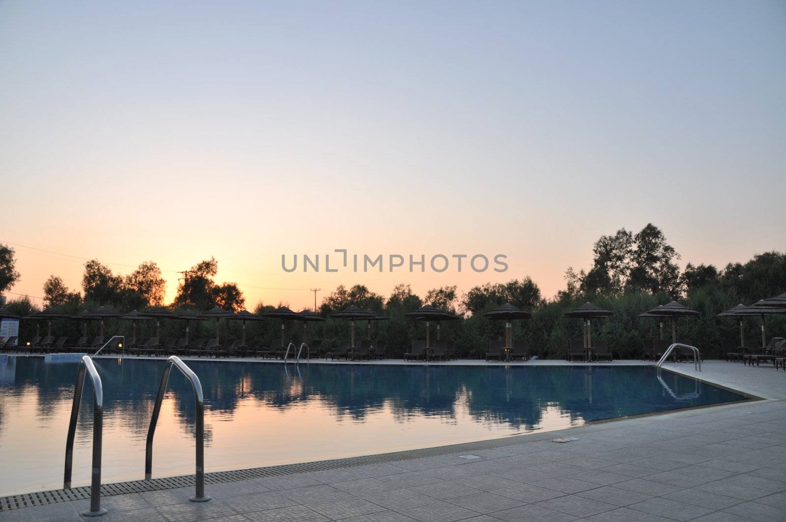 gorgeous resort swimming pool with umbrellas during sunset
