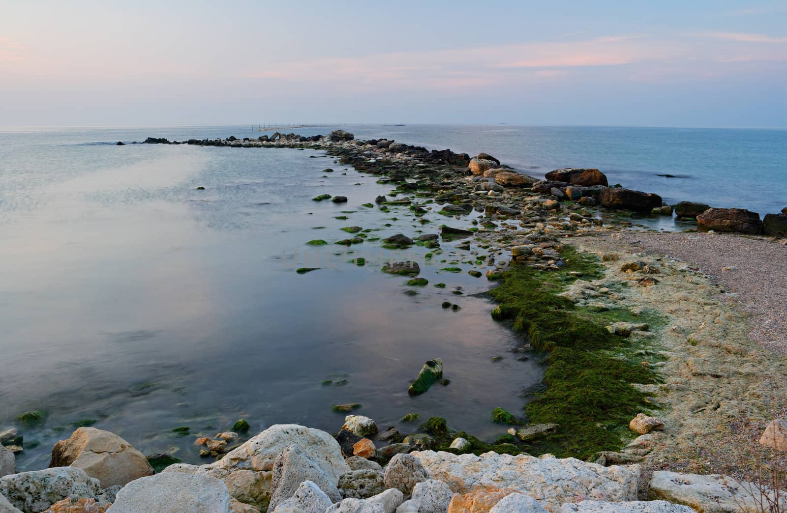 Breakwater in morning light with calm sea water