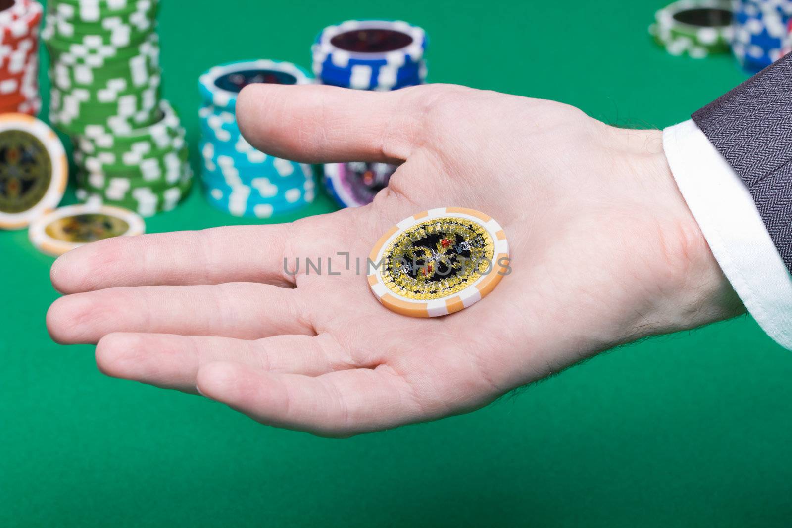 poker chips in the palm of a man on a background of green gambling table
