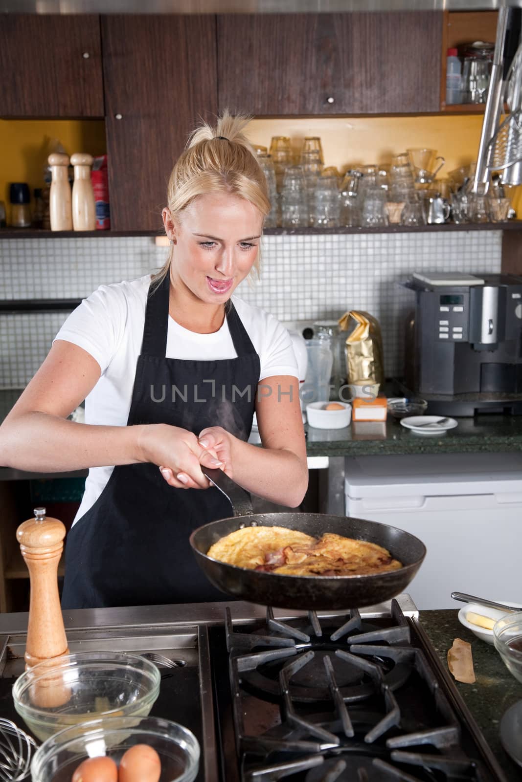 Female chef looking concentrated at the frying pan about to flip her egg