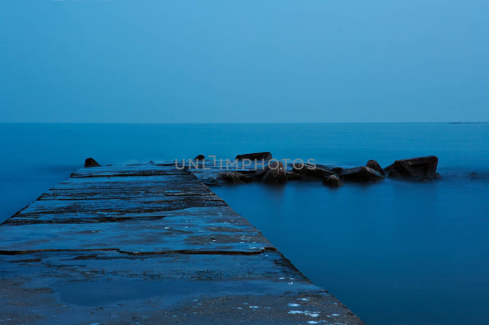 Old stone quay in calm sea and blue moonlight