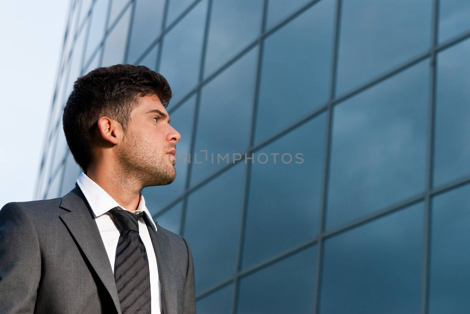 Young businessman looking good expectations on modern building background by dgmata