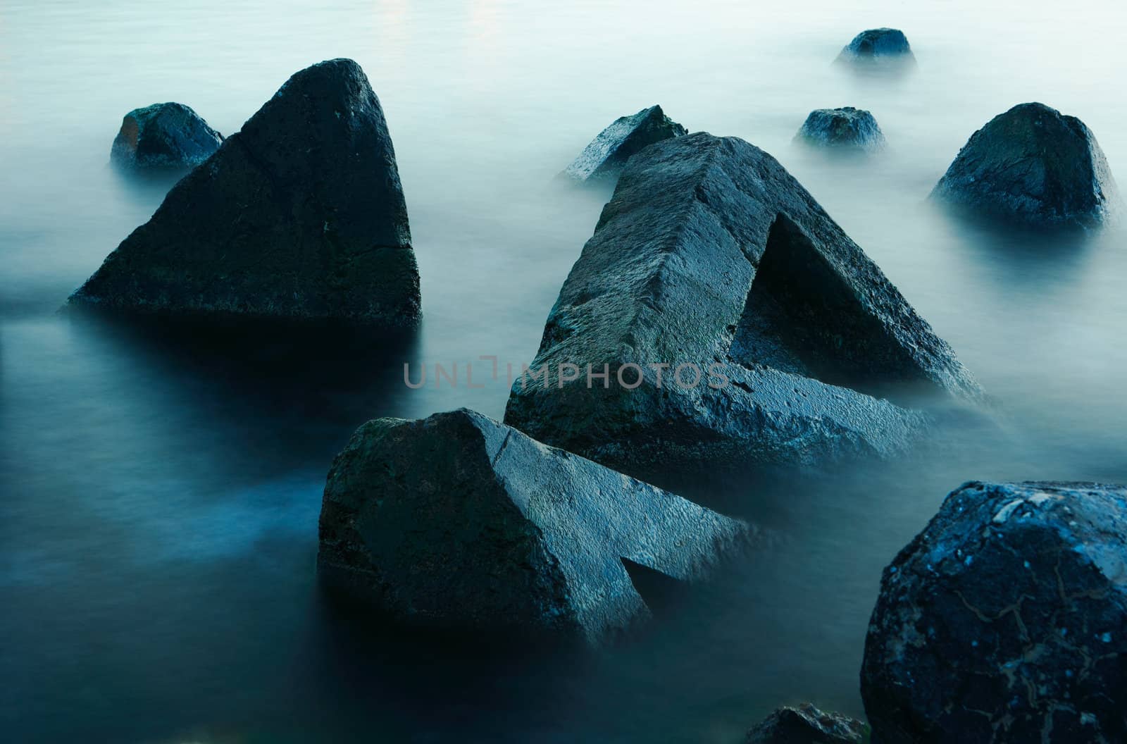 Stones in smooth sea water, movement blured surface