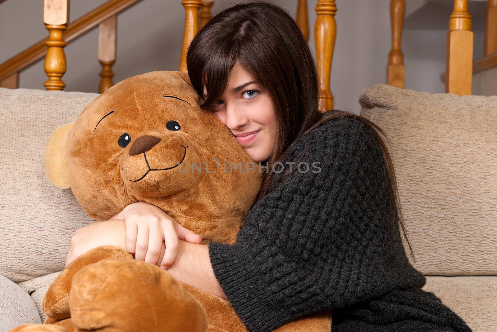 Young woman embracing teddy bear sitting on sofa close-up by dgmata