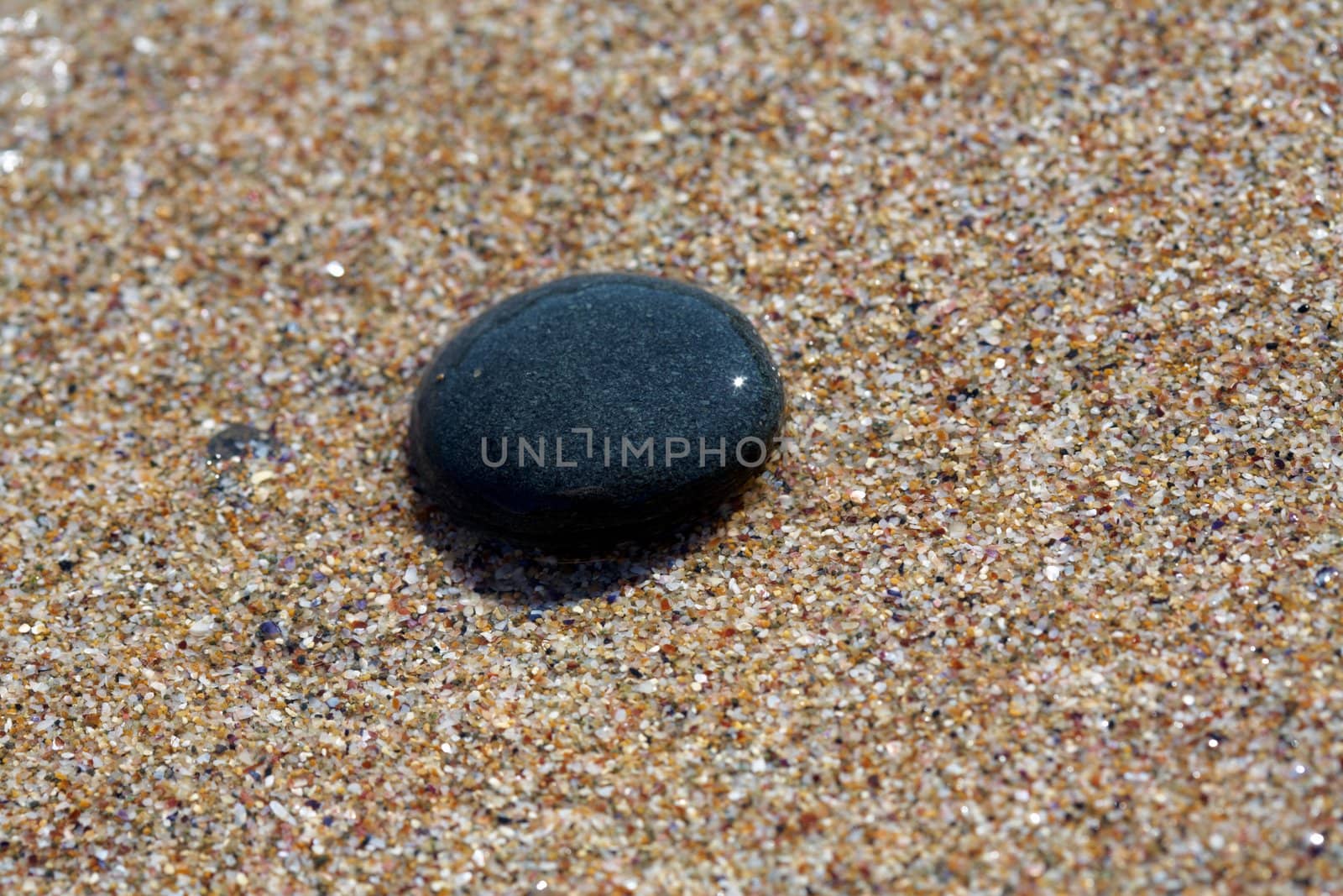 Black SPA stone on the beach sand