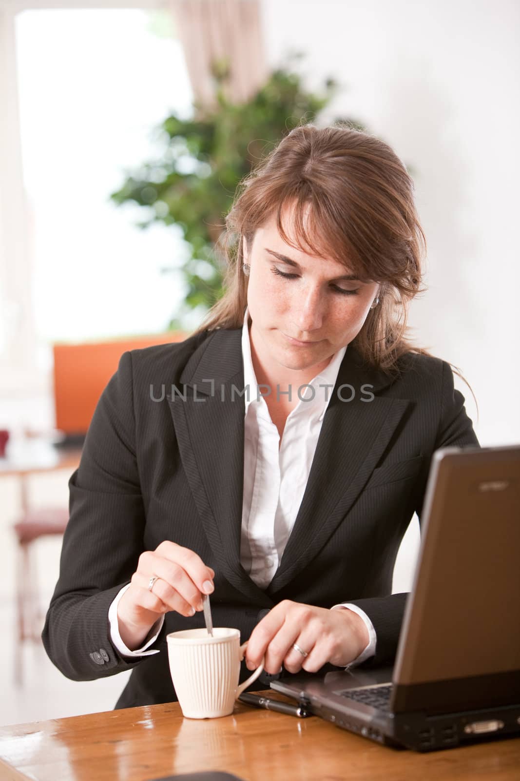Attractive young businesswoman behind her desk with coffee