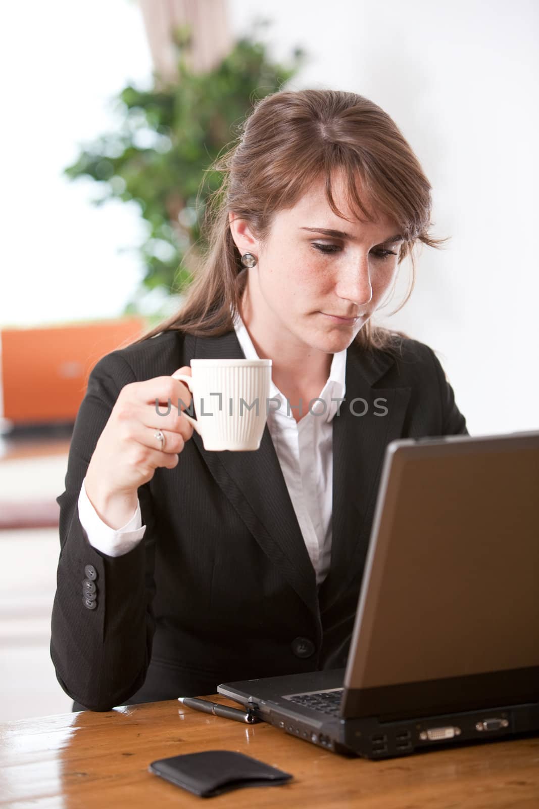 Attractive young businesswoman having a coffee while checking her email